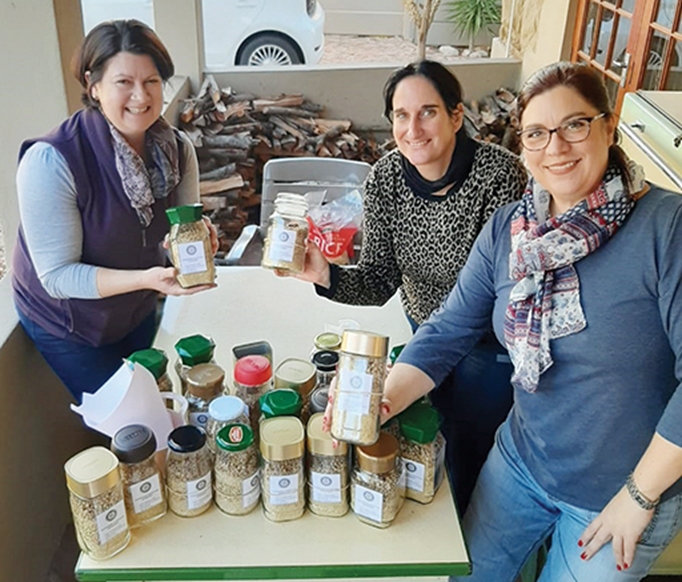 Saretha Conrade (links), Dalia Wilck (middel) en Lezelma Pretorius van die Oudtshoorn Rotariërs besig om die Jars of Hope met droë sopbestanddele te vul.